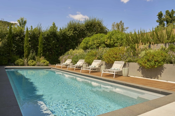 Symmetrical row of luxury white sun loungers by a pristine outdoor pool, premium lifestyle location by Love Locations.