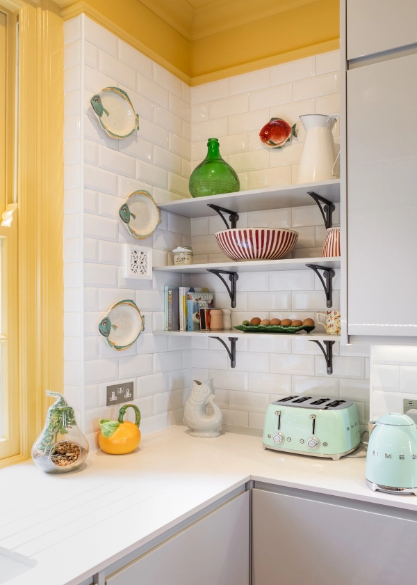 Quirky kitchen corner location in Westminster SW1V for brand shoots by Love Locations, showcasing open white shelving, a pastel green toaster, and a yellow tiled accent.
