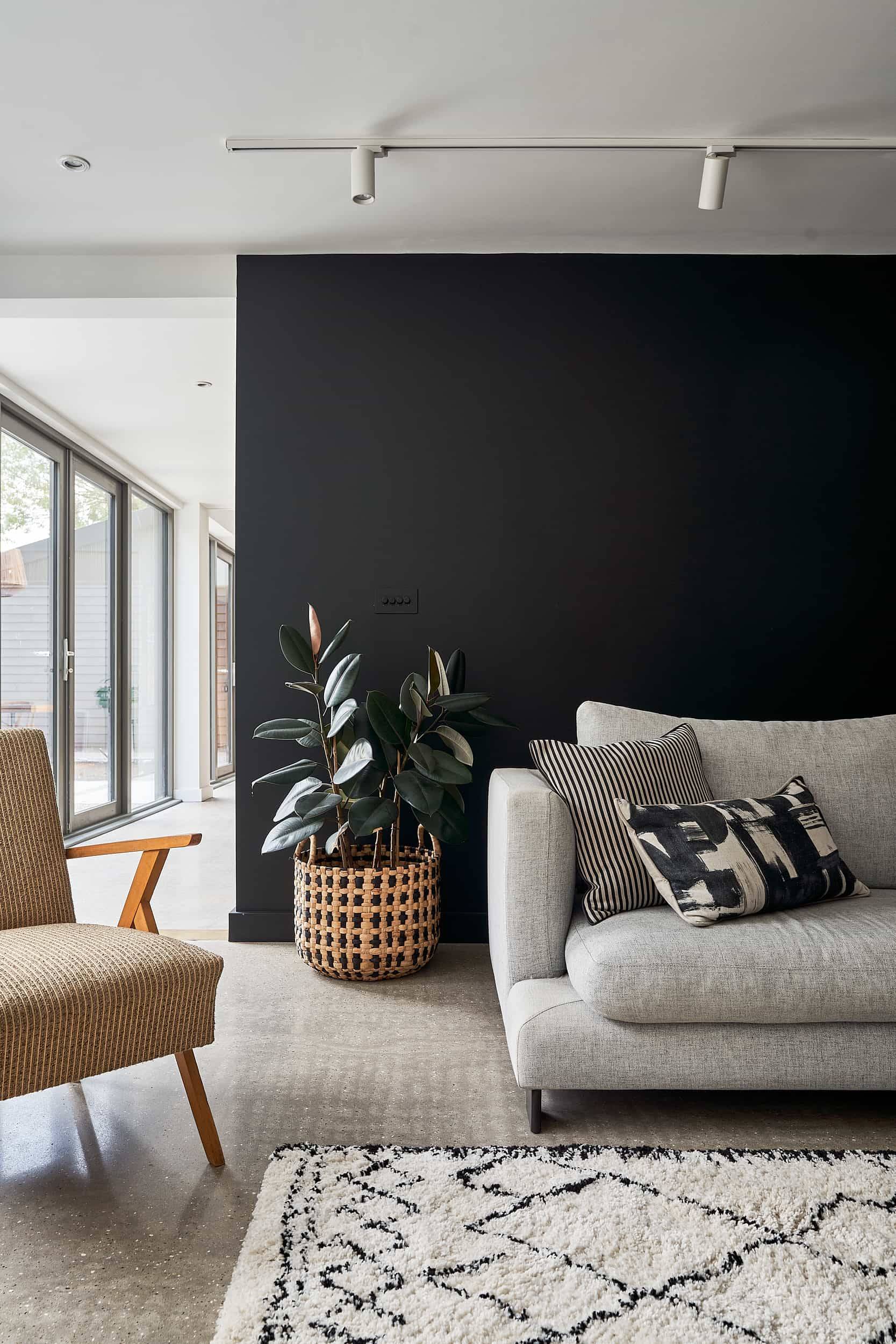 Modern sitting area with a light grey sofa set against a dark charcoal feature wall with houseplant accents, Love Locations IP30.
