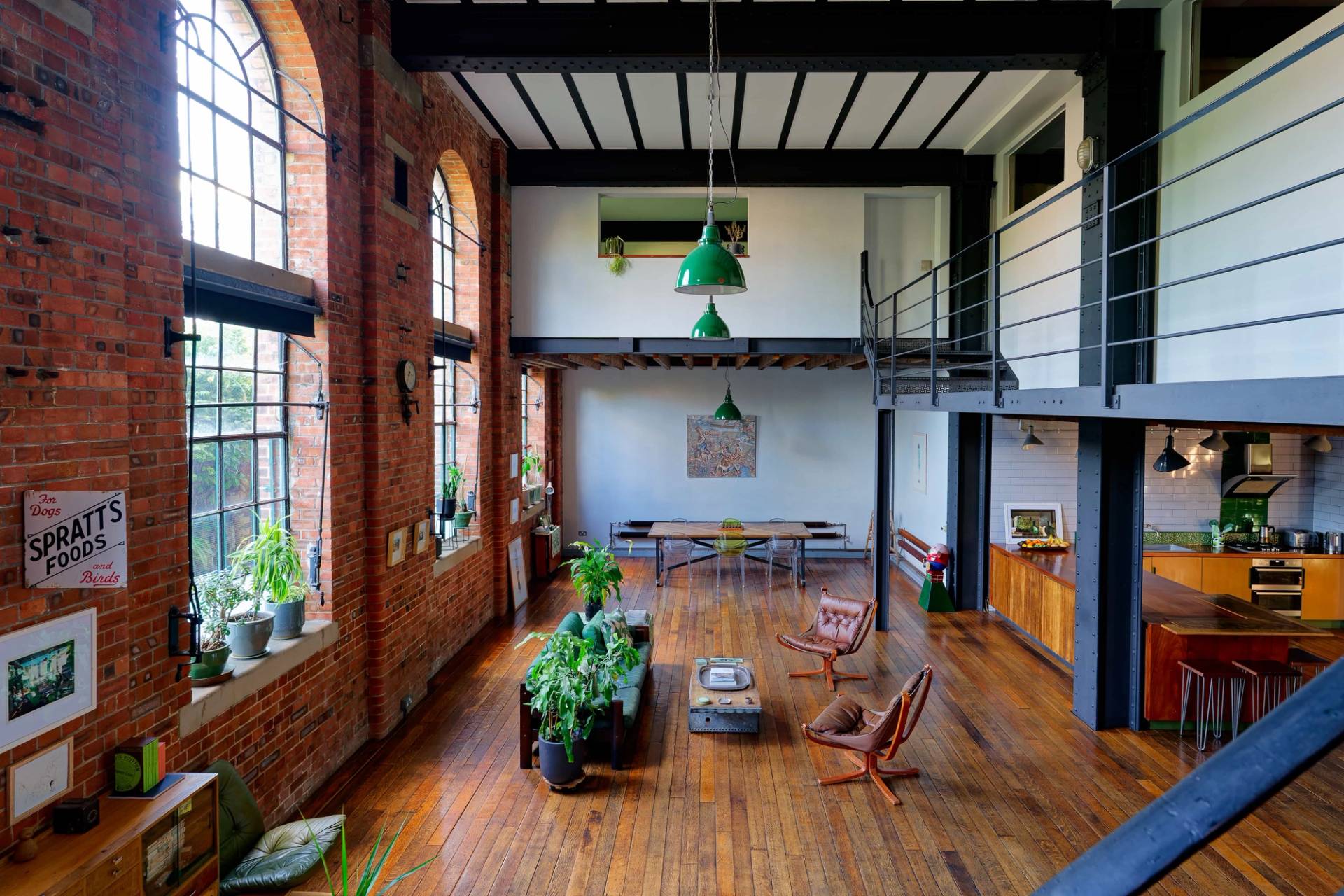 Industrial converted warehouse shoot location in Tower Hamlets, E14 featuring double-height exposed red brick walls, high ceilings, timber floors, and green pendant lights via Love Locations.