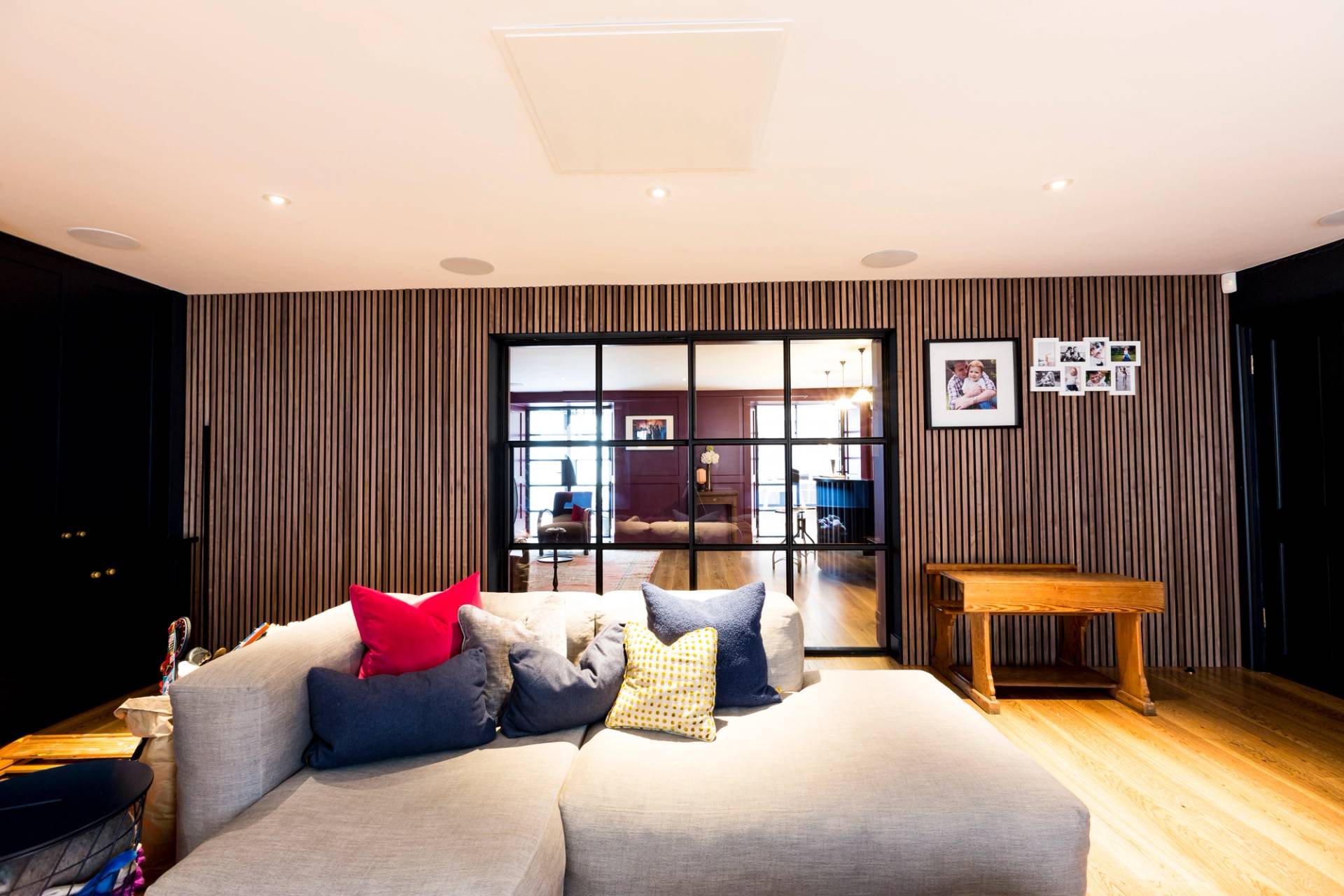 Modern cinema media room location in Camberwell, SE5 featuring grey modular sofa and acoustic wood slat wall panelling via Love Locations.