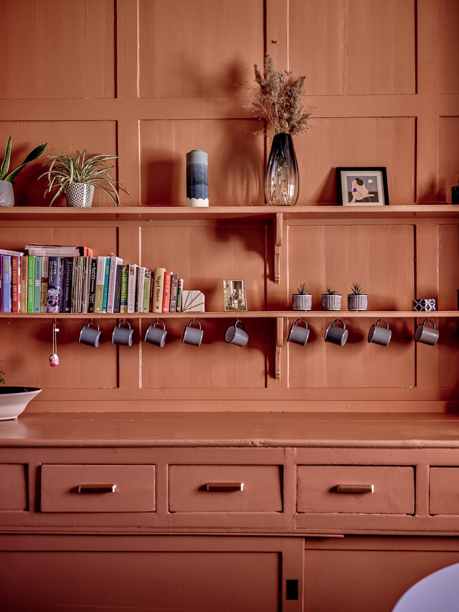 Built-in terracotta orange dresser unit with open mug shelves and drawers, ideal for domestic brand ads, Love Locations ME13.