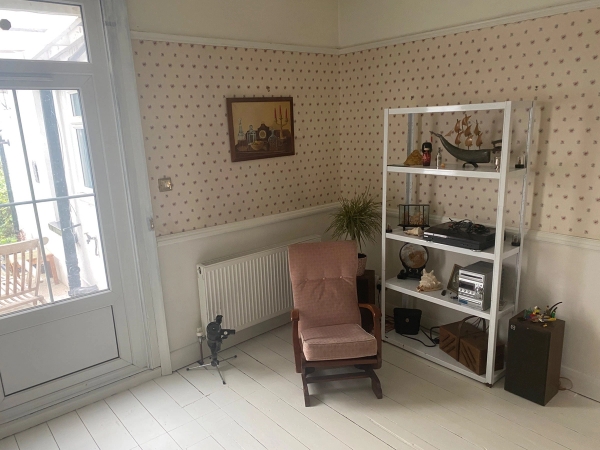 Eclectic seating corner with an antique rocking chair, white shelving unit, and painted timber floors, suitable for vintage lifestyle brand shoots, Love Locations.
