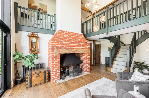 Traditional red brick inglenook fireplace with an overhead timber mezzanine landing balcony, unique location house via Love Locations.