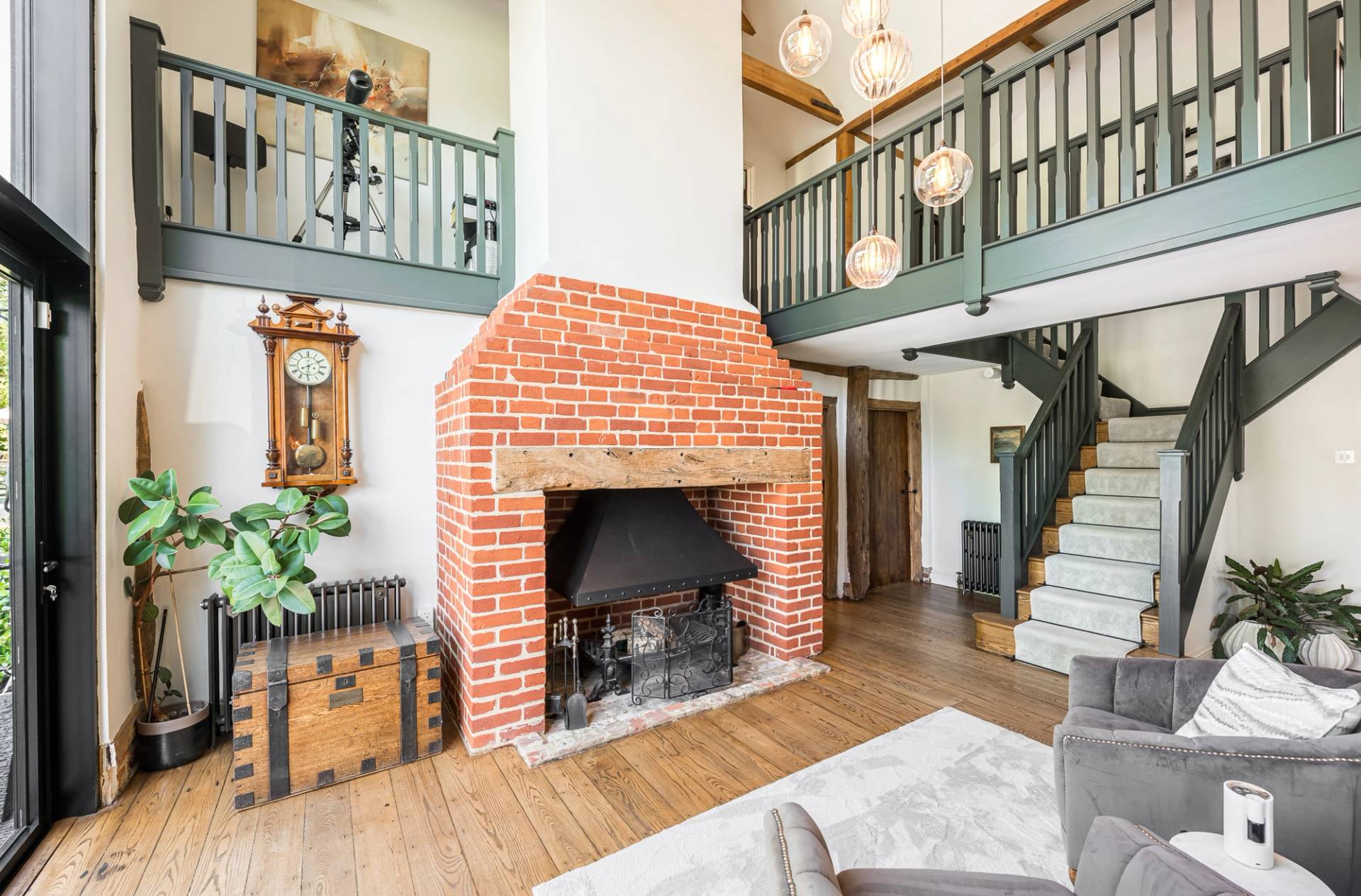 Traditional red brick inglenook fireplace with an overhead timber mezzanine landing balcony, unique location house via Love Locations.