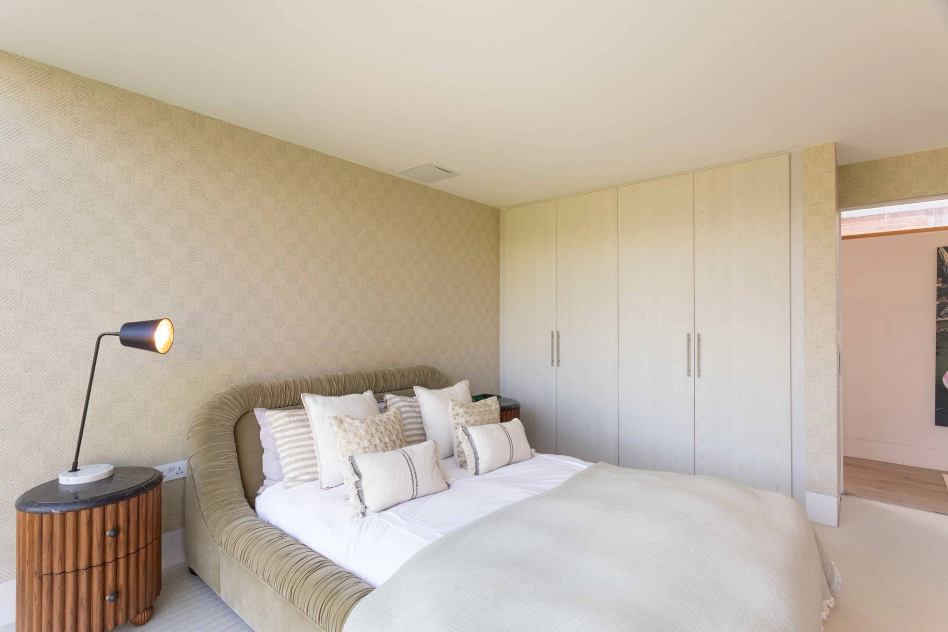 Love Locations clean aesthetic bedroom Surrey: Bright minimalist bedroom featuring seamless floor-to-ceiling white wardrobes, excellent for clothing or product backdrops.