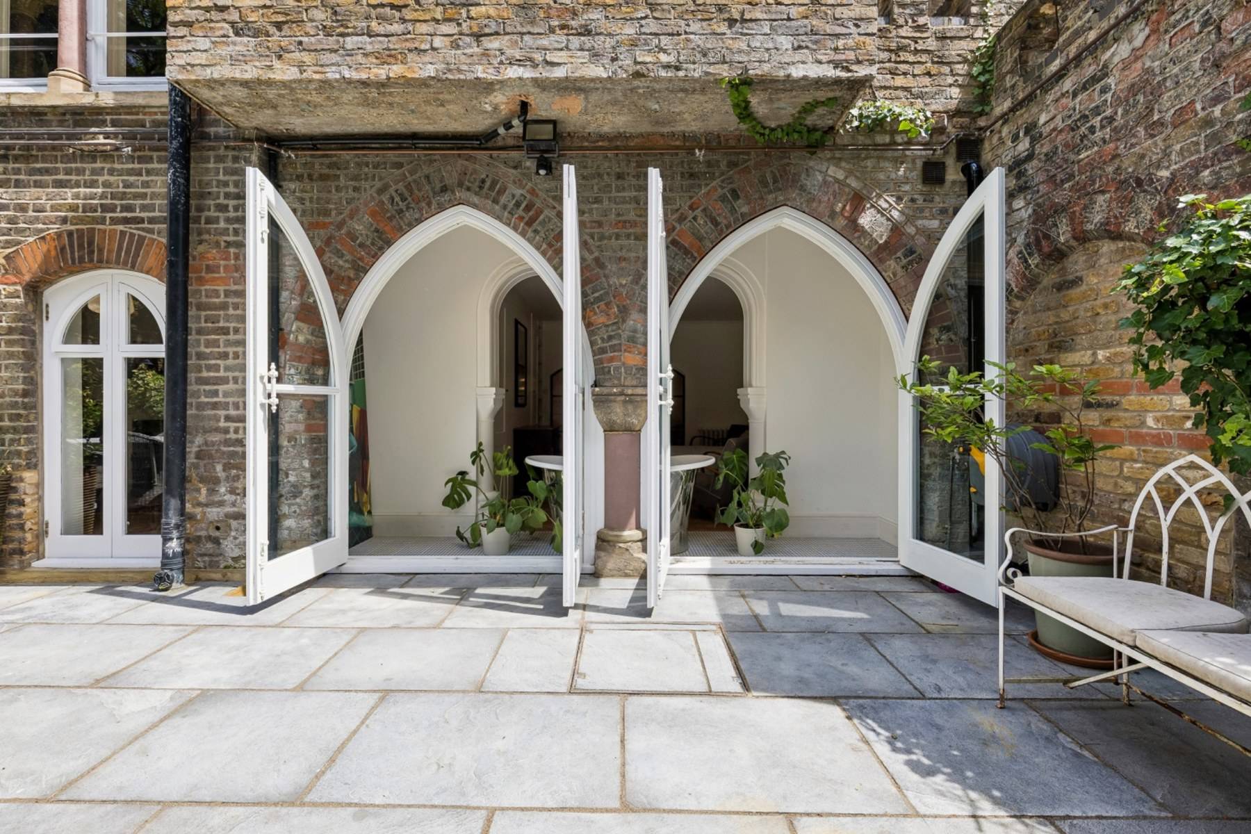 Gothic brick arched garden doors opening onto a paved patio terrace in Hampstead NW3 by Love Locations.