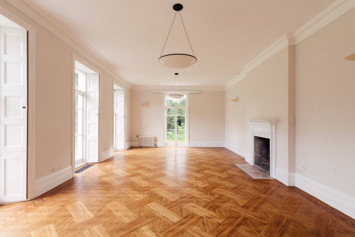 Grand parquet reception room with a white marble fireplace surround, pendant light, and triple sash windows, ideal for period drama filming, Love Locations SE15.