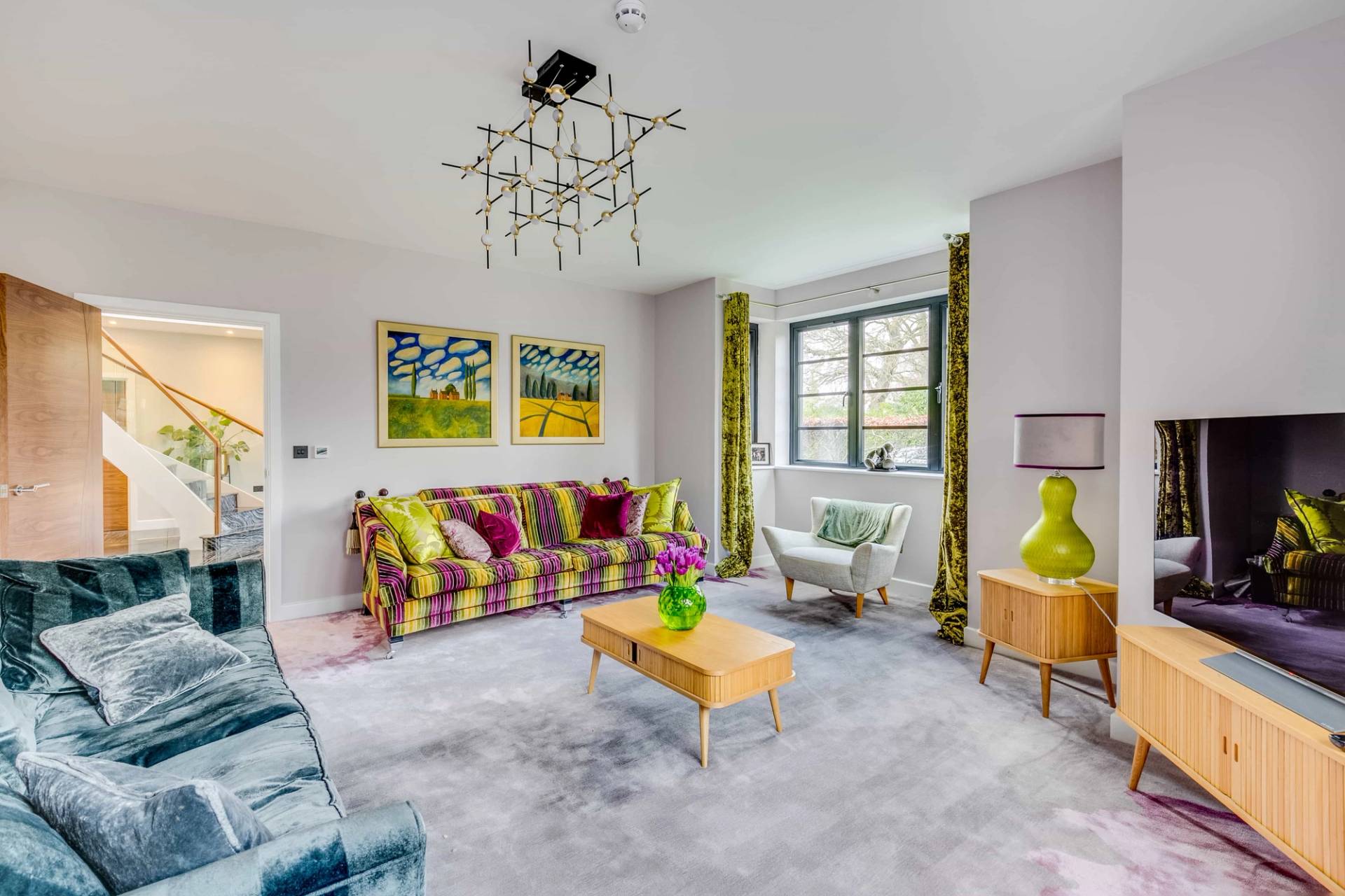 Formal sitting room featuring a colorful striped sofa, grey carpet, lime green table lamps, and yellow armchair, Love Locations CB2.