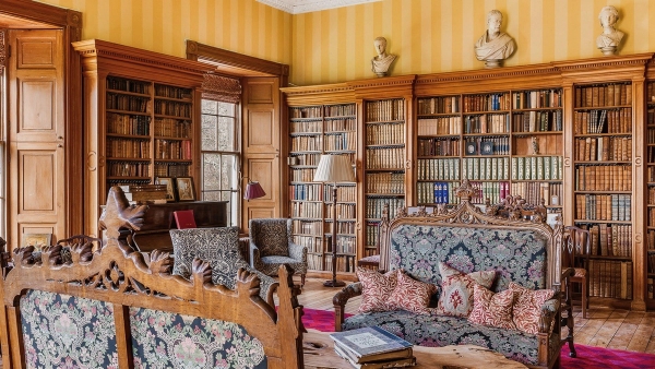 Historic castle library lined with floor-to-ceiling bookfilled shelves and tapestry armchairs, Love Locations KY15.