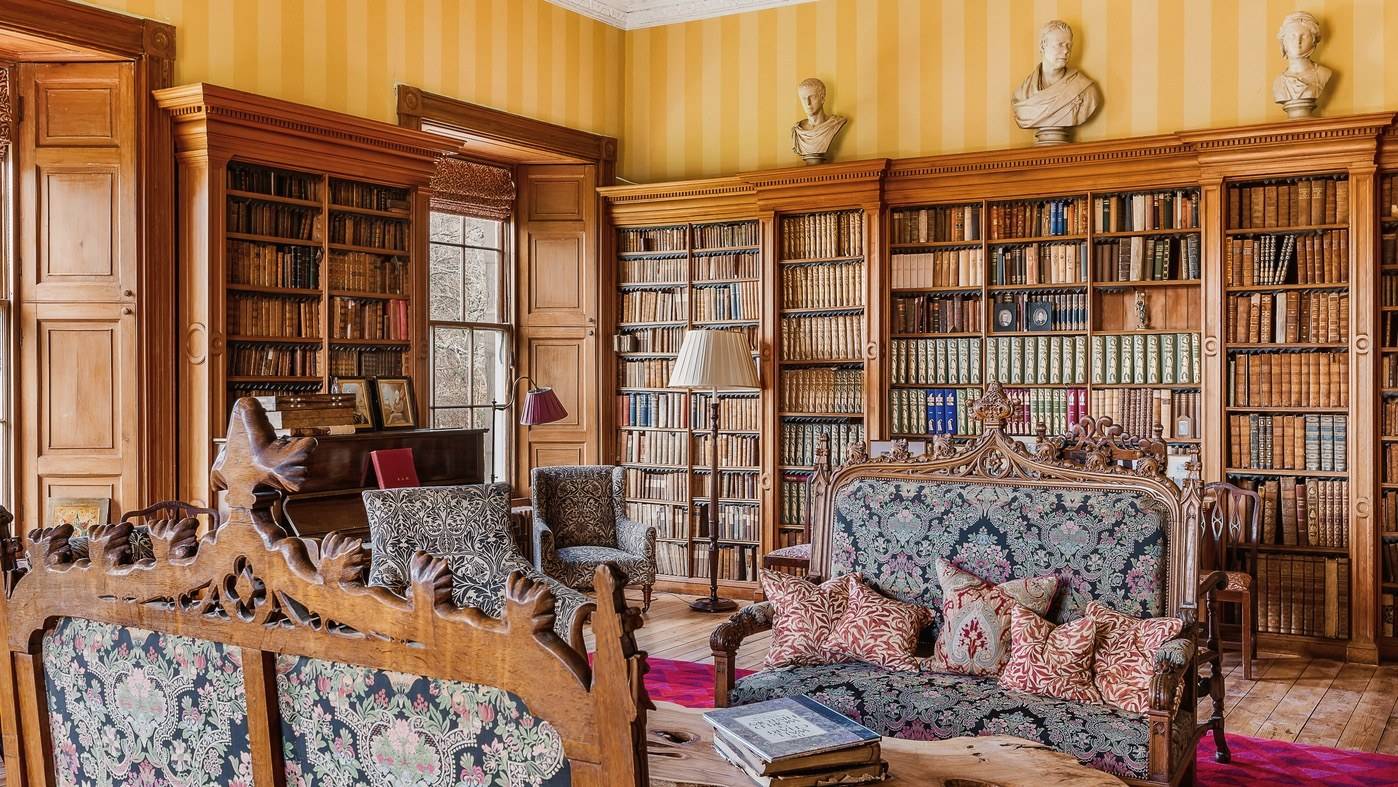 Historic castle library lined with floor-to-ceiling bookfilled shelves and tapestry armchairs, Love Locations KY15.