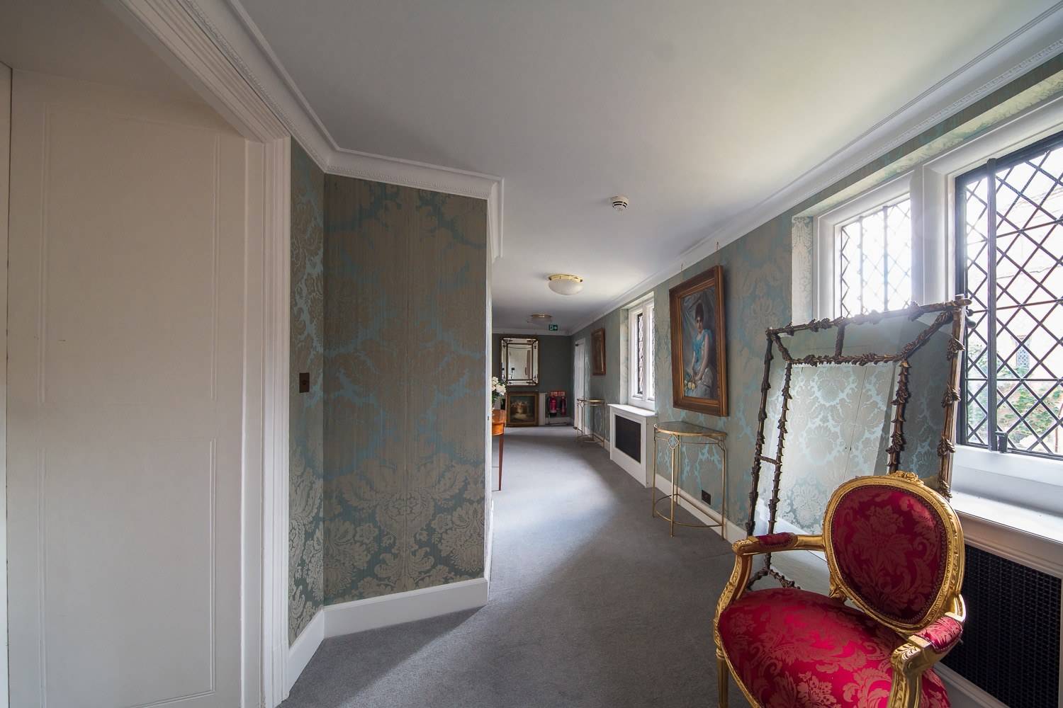 Light-filled upper landing and corridor with blue damask wallpaper in a Hertfordshire country house from Love Locations.