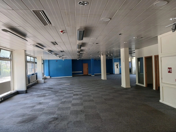 Gritty, empty warehouse-style office backdrop for production hire in Watford WD18 via Love Locations, with textured square flooring and a blue accent wall.