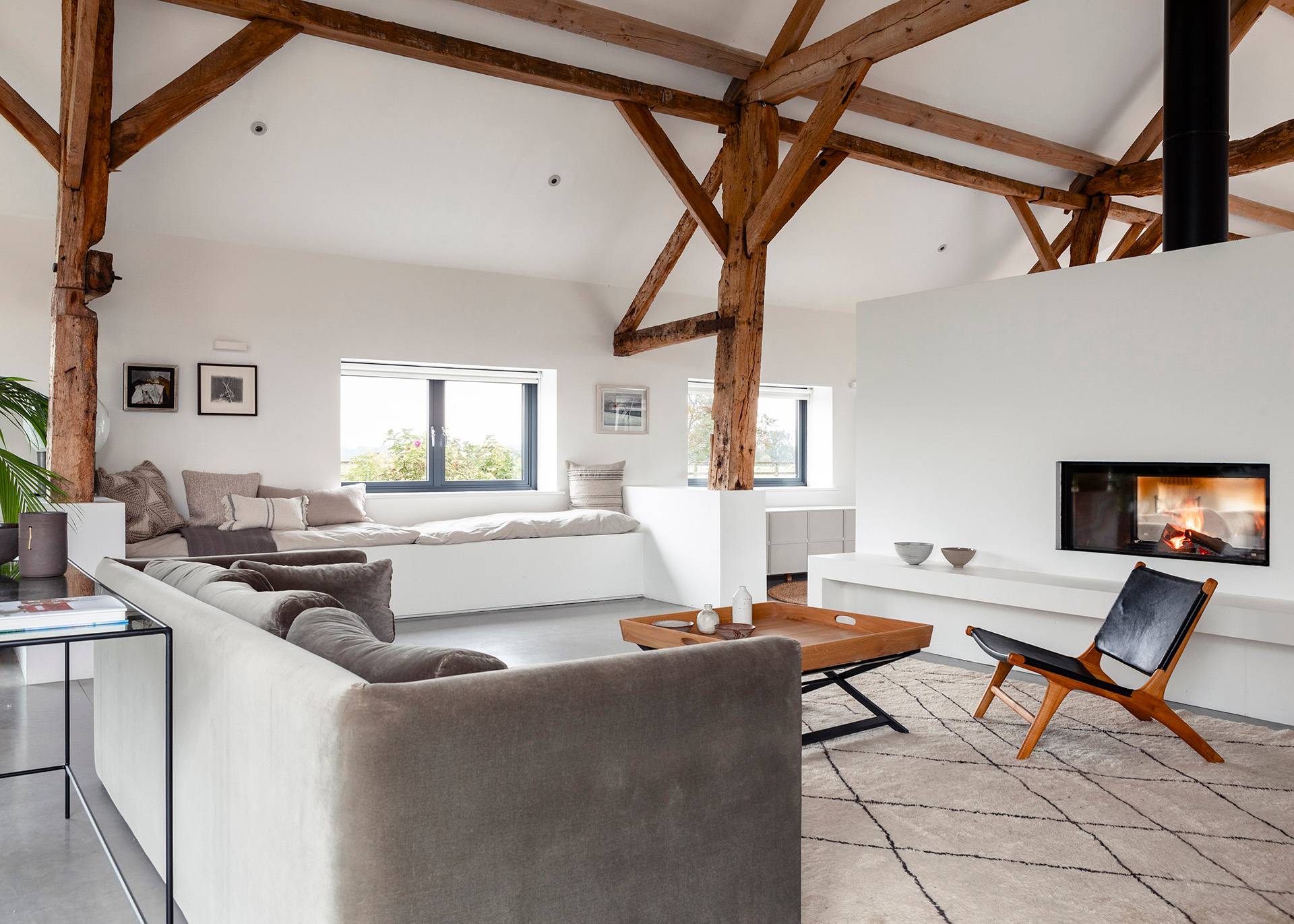Open-plan seating area with grey velvet sofa, rustic coffee table, and polished concrete flooring in SN8, Love Locations.