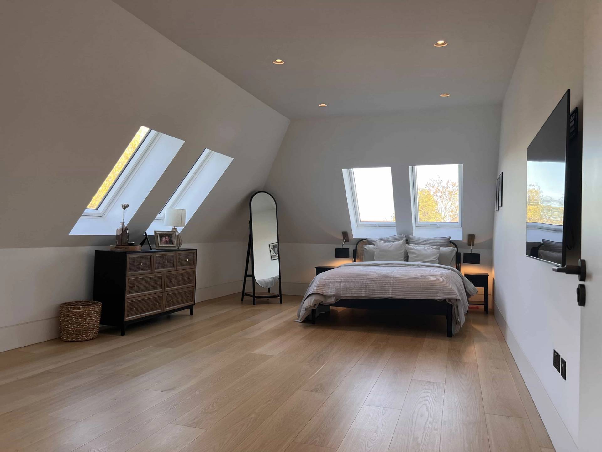 Top-floor attic bedroom with sloped ceilings, skylight windows, and light wood flooring, ideal for cozy lifestyle filming, Love Locations.