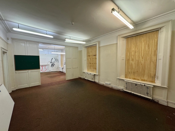 Abandoned commercial property room featuring heavy security window boarding and mismatched doors for thriller sets, Love Locations.
