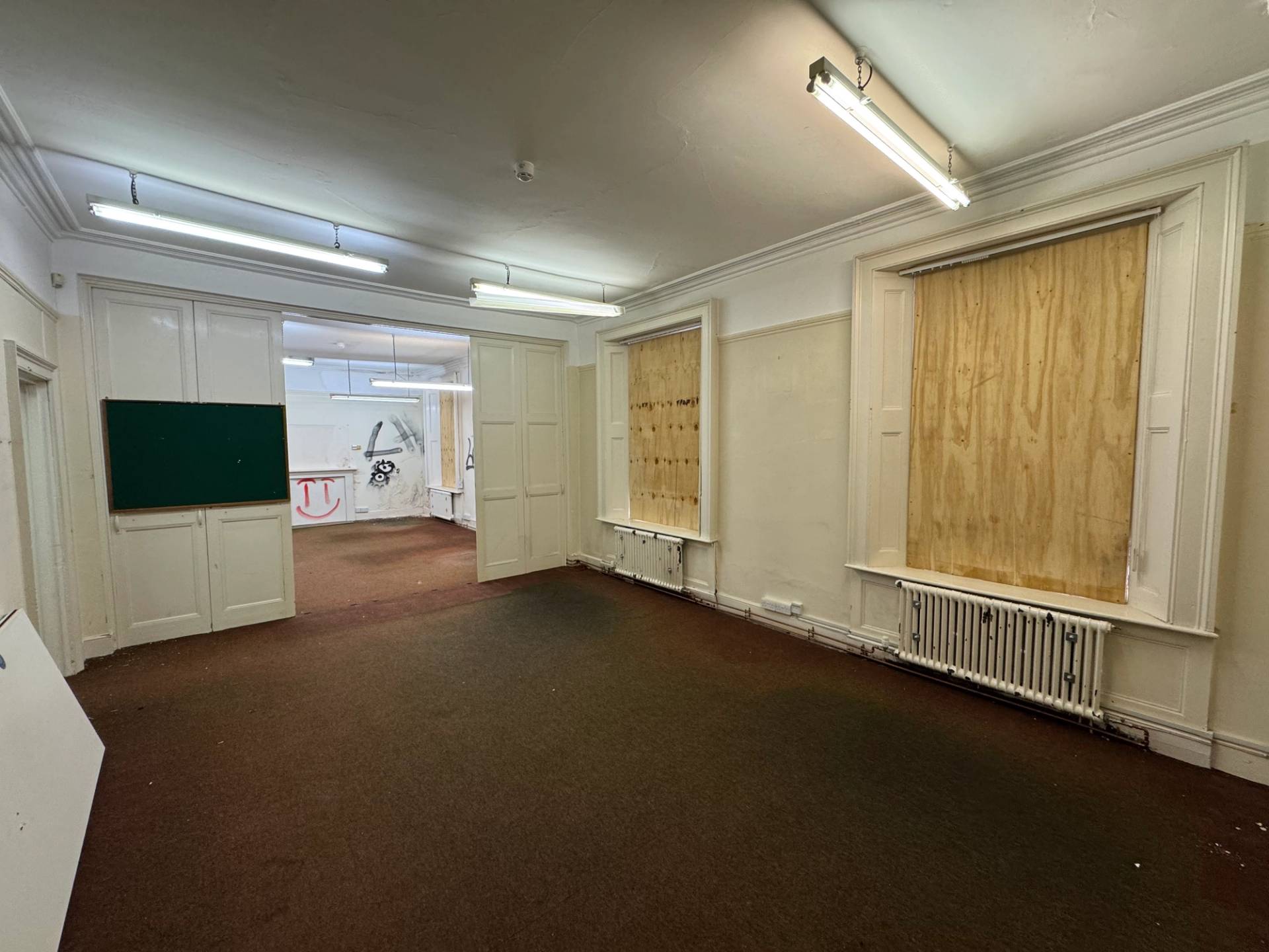 Abandoned commercial property room featuring heavy security window boarding and mismatched doors for thriller sets, Love Locations.