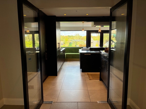 Sleek open-plan kitchen and dining transition hall in Essex CM4 available via Love Locations, framed by modern black-framed glass bi-fold doors.