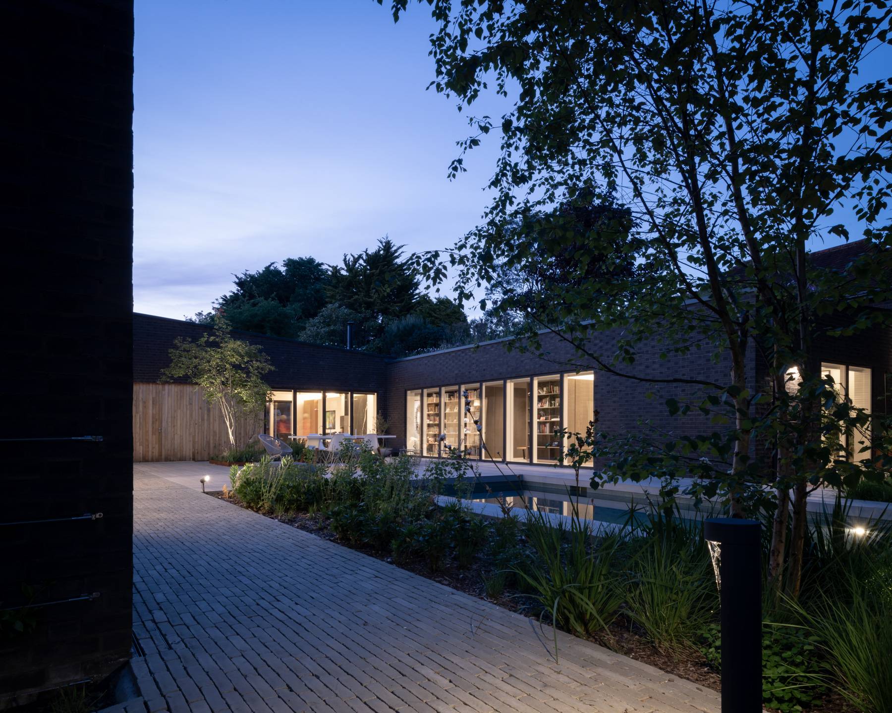 Twilight view of a dark architectural house and gravel driveway set against evening skies, Love Locations BN3.