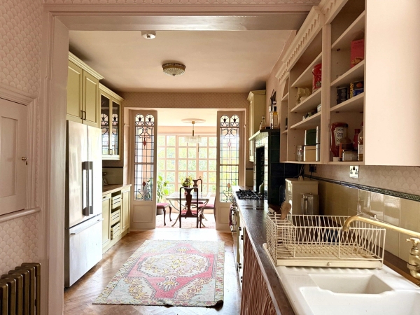 Perspective view through a light-filled Edwardian kitchen towards stained glass garden doors, Love Locations N13.