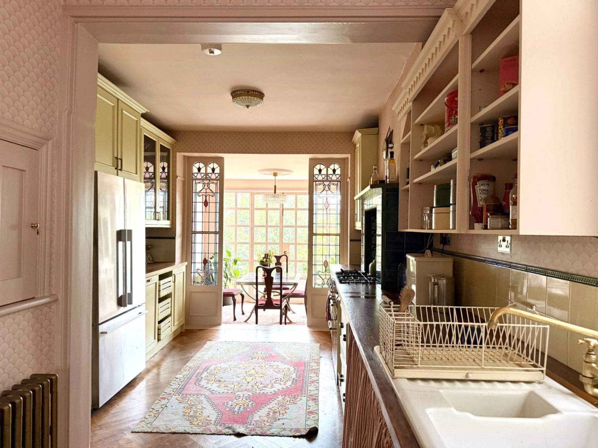 Perspective view through a light-filled Edwardian kitchen towards stained glass garden doors, Love Locations N13.