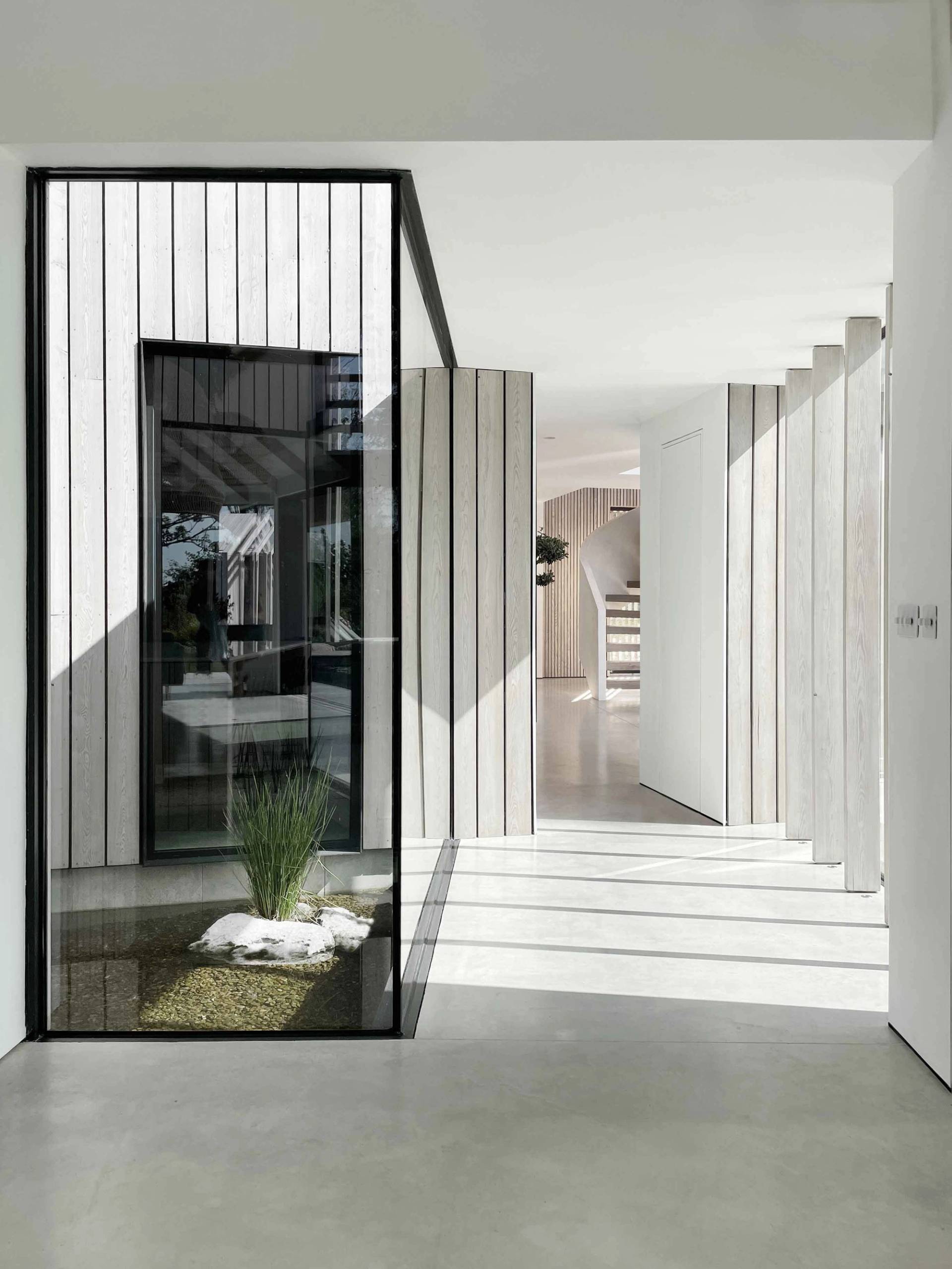 Minimalist hallway corridor lined with slatted wooden panel walls, polished concrete floors, and glass partitions, Love Locations.