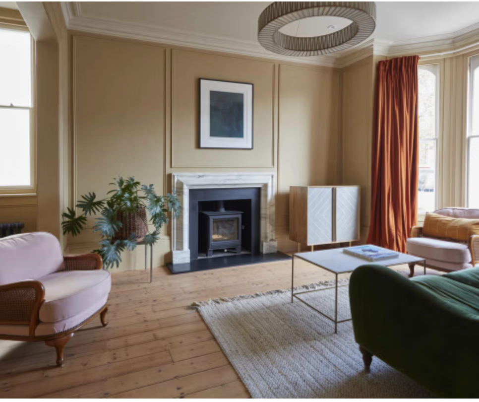 Elegant reception room at Crescent House with fireplace, panelled walls, wooden floorboards and warm heritage-inspired interiors.