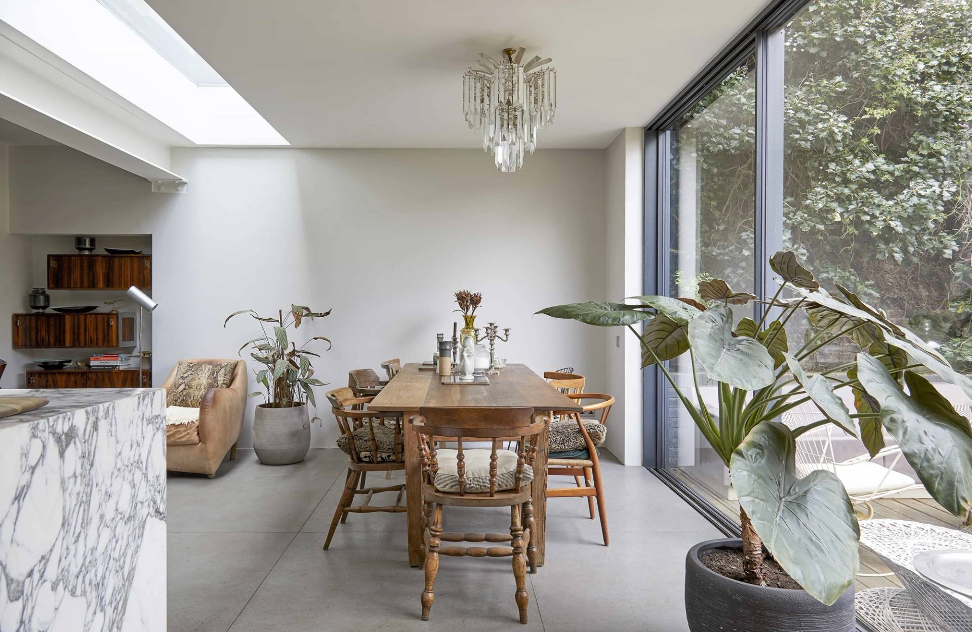 Light-filled dining nook with a wooden dining table, classic chairs, skylight, and large sliding doors, Love Locations N16.
