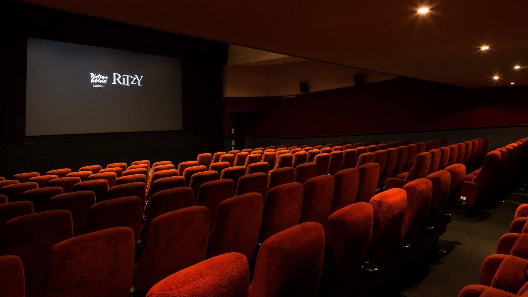 Side perspective shot highlighting rows of classic red velvet cinema seating and the widescreen projection display inside The Ritzy Screen 2 venue hire by Love Locations.