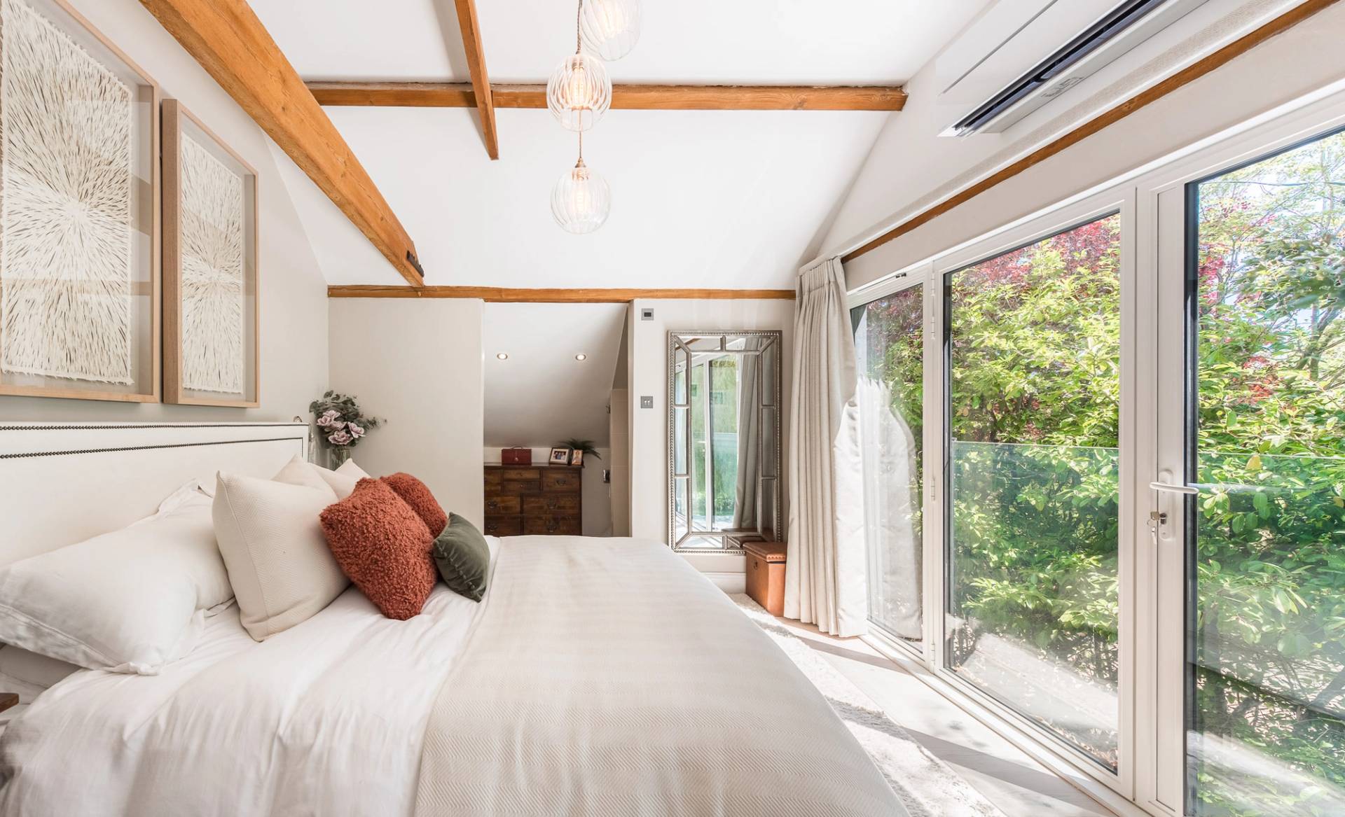 Minimalist barn conversion bedroom with extensive white fitted wardrobes and scenic country views, through Love Locations.
