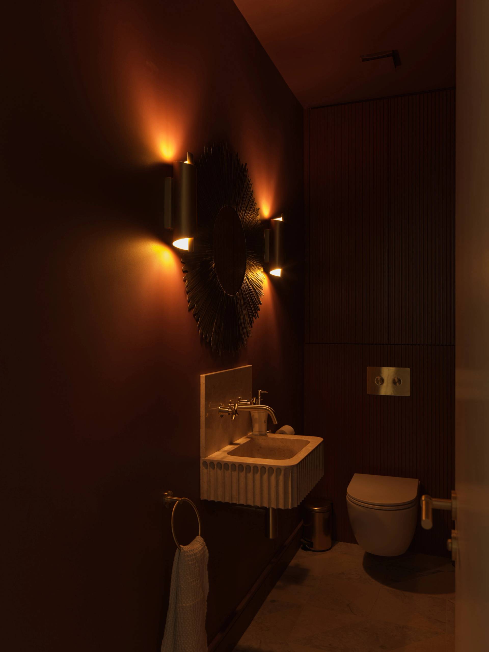 Atmospheric dark powder room shoot location with mood wall sconce lighting and floating stone washbasin via Love Locations.