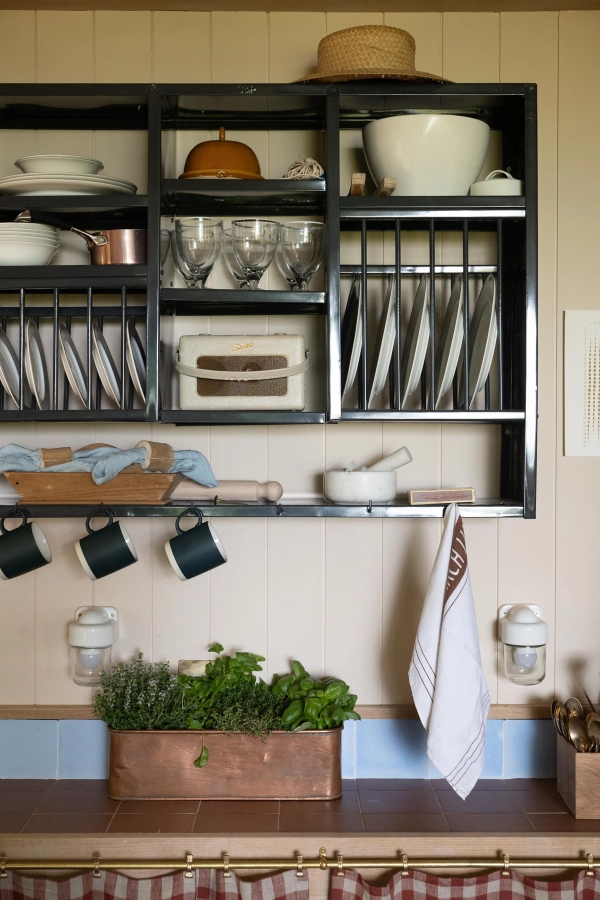 Traditional black wooden plate rack shelf over a blue tiled splashback inside a luxury cabin location house, ideal for homeware product photography via Love Locations.