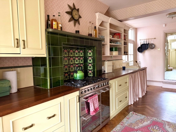 Kitchen counter layout featuring green glazed wall tiles, wooden worktops, and Range cooker, Love Locations N13.