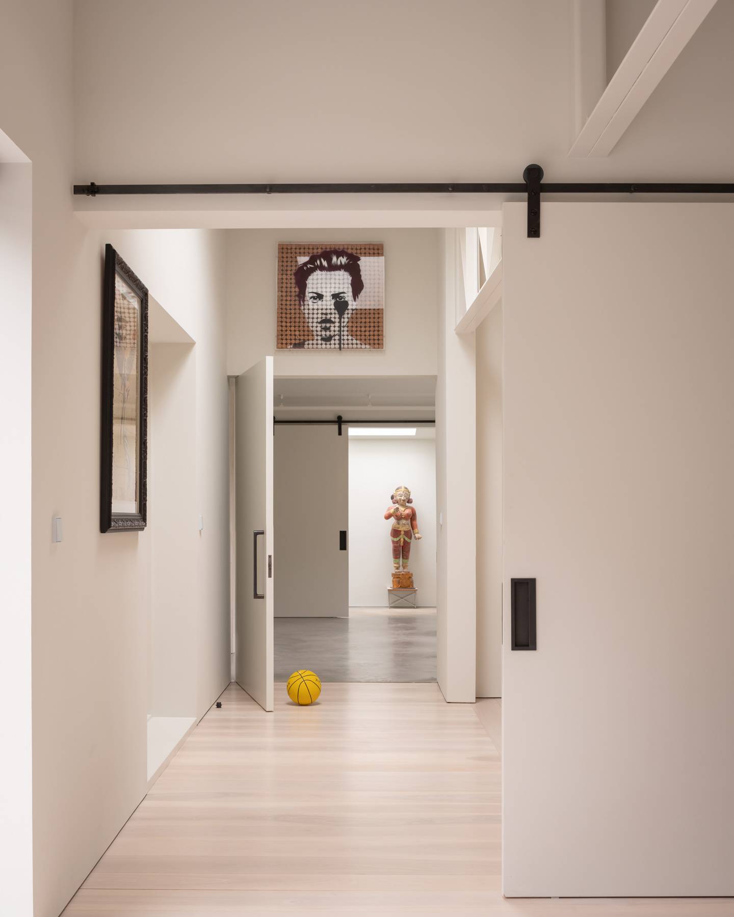 Sliding pocket door transition into a sunlit art gallery corridor with white painted floorboards, Love Locations BN3.