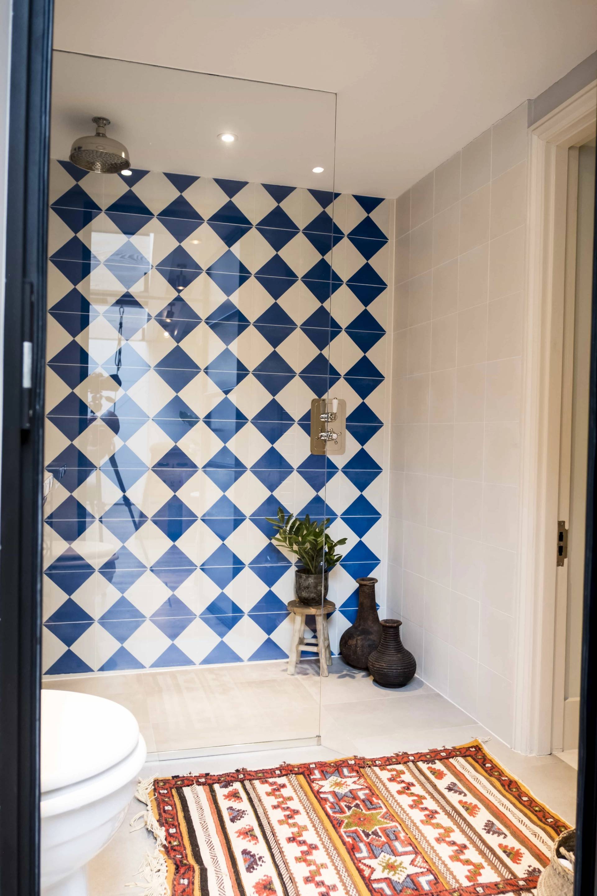 Walk-in shower enclosure featuring bold blue and white diagonal diamond pattern tiles in SE5 via Love Locations.