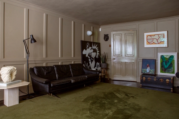 Classic reception room with grey wall panelling, black leather couch, and white panelled doorway in Faversham, Love Locations ME13.