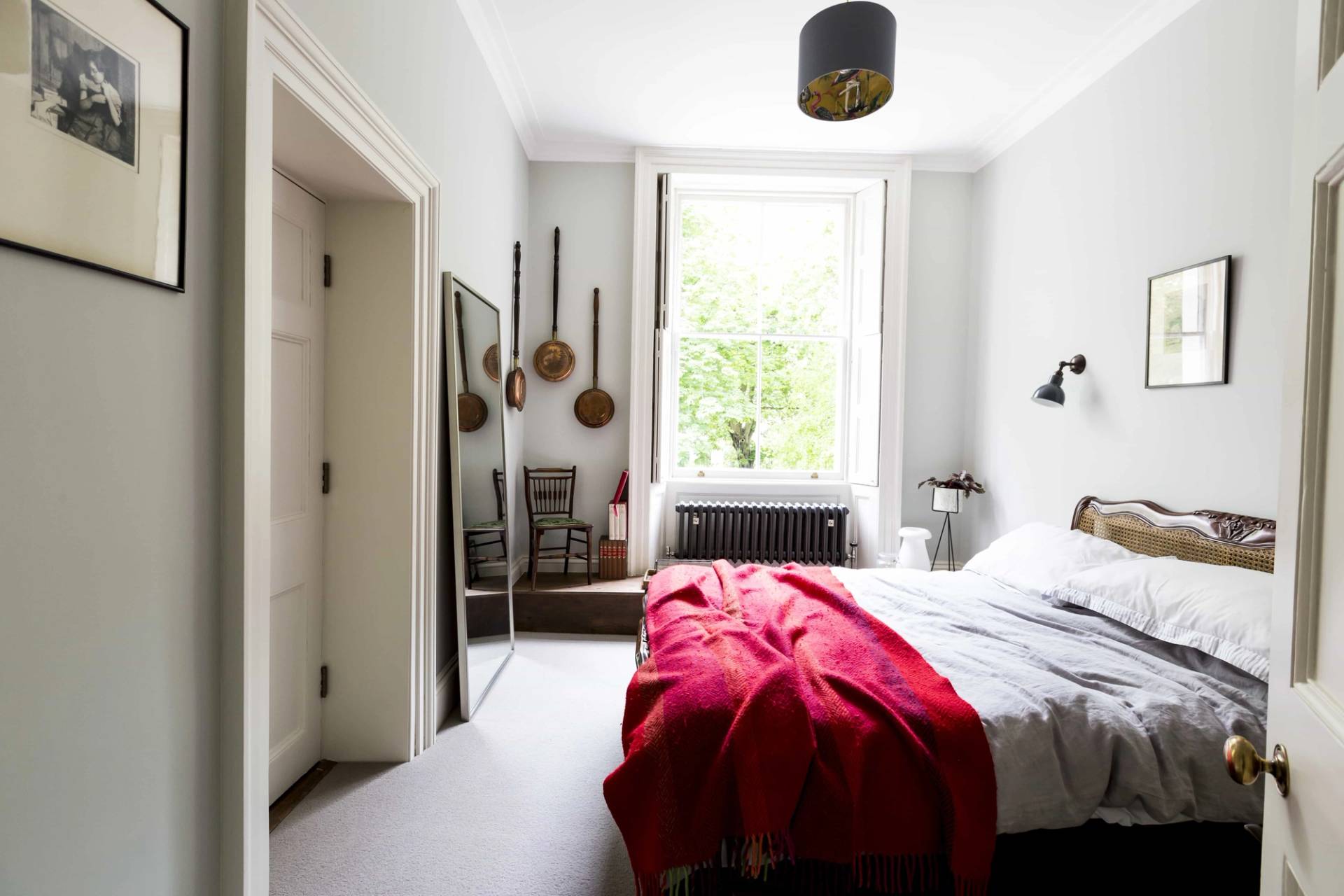Minimalist bedroom location in Camberwell, SE5 featuring red bedding, neutral walls, and sash window views via Love Locations.