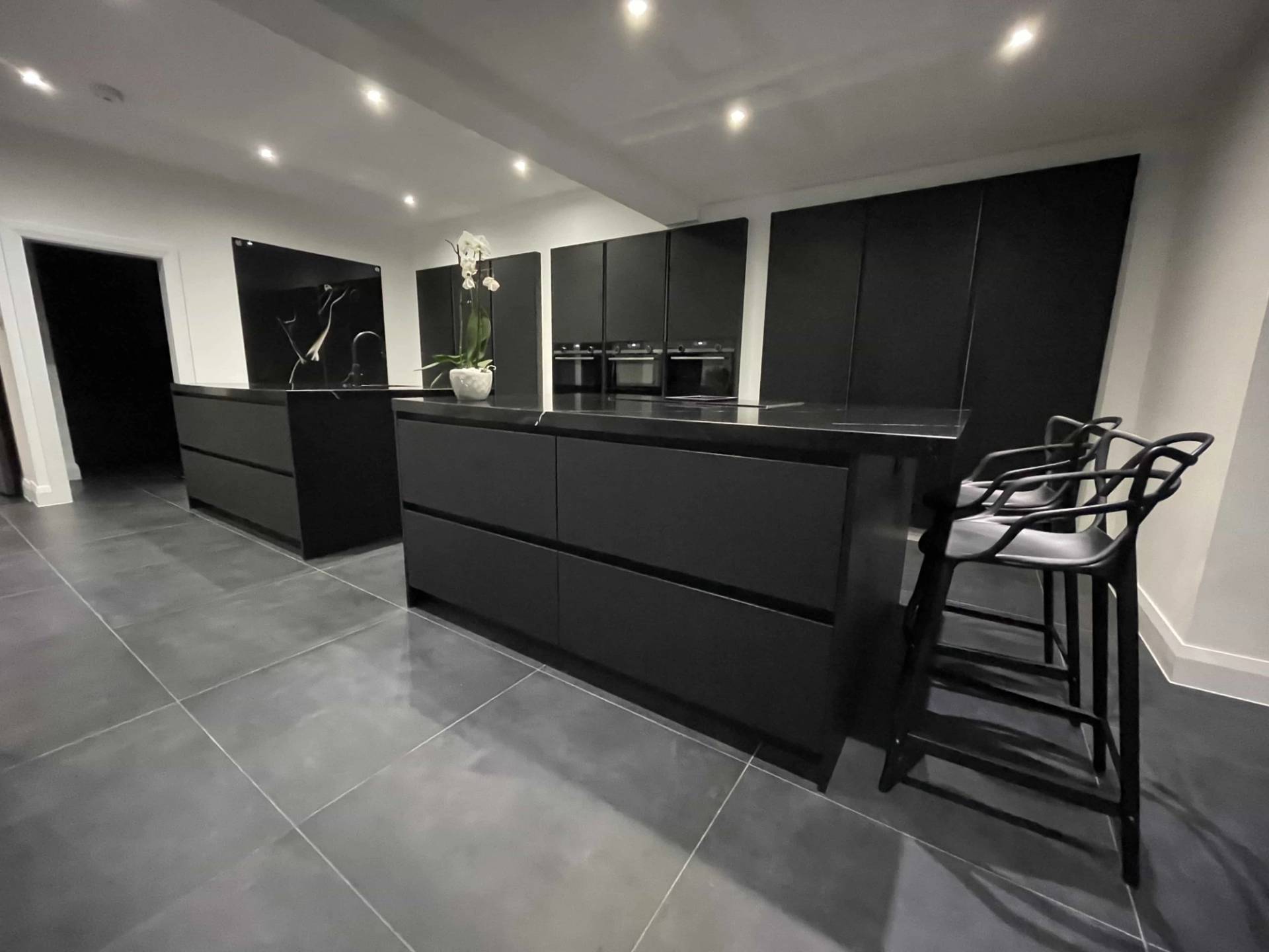 Matte black luxury kitchen featuring a waterfall marble breakfast bar and modern bar stools, ideal for high-end food media shoots, Love Locations IG10.