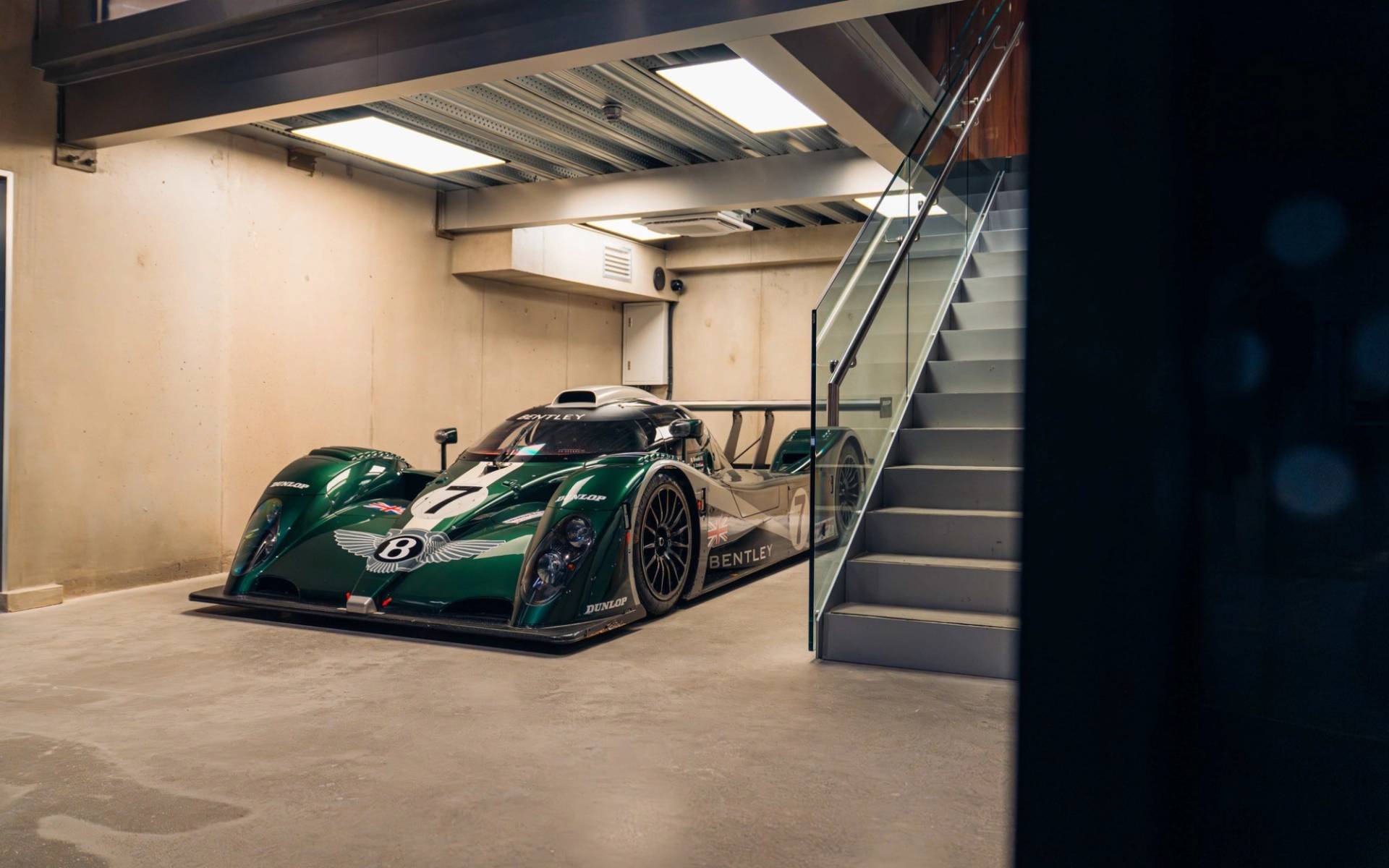 Green classic Le Mans race car parked beside a modern staircase in a shoot location house from Love Locations.