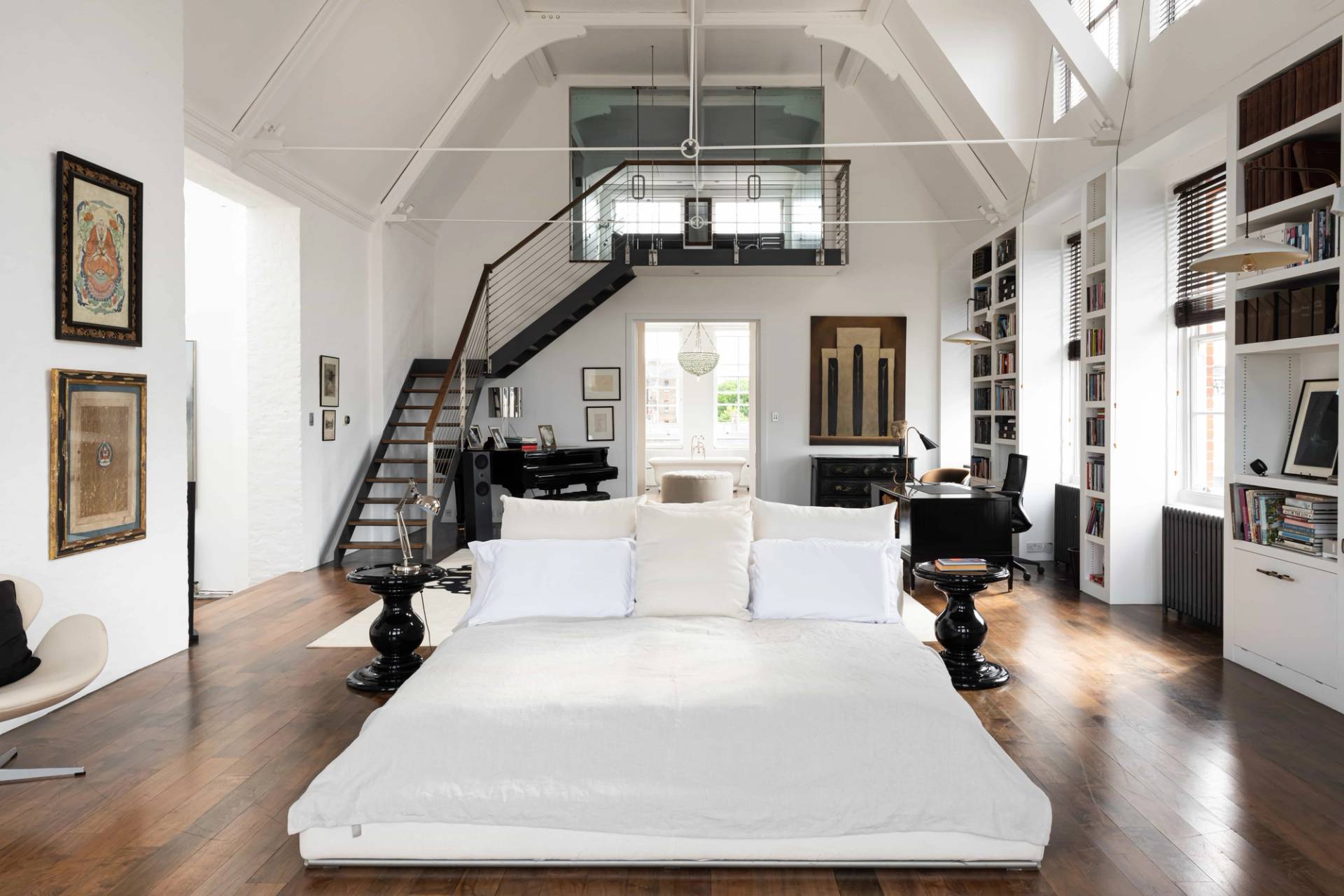 Vaulted master bedroom suite with a low-profile bed, white painted roof trusses, and industrial pendant lighting, ideal for mattress and sleepwear brand ads, Love Locations.