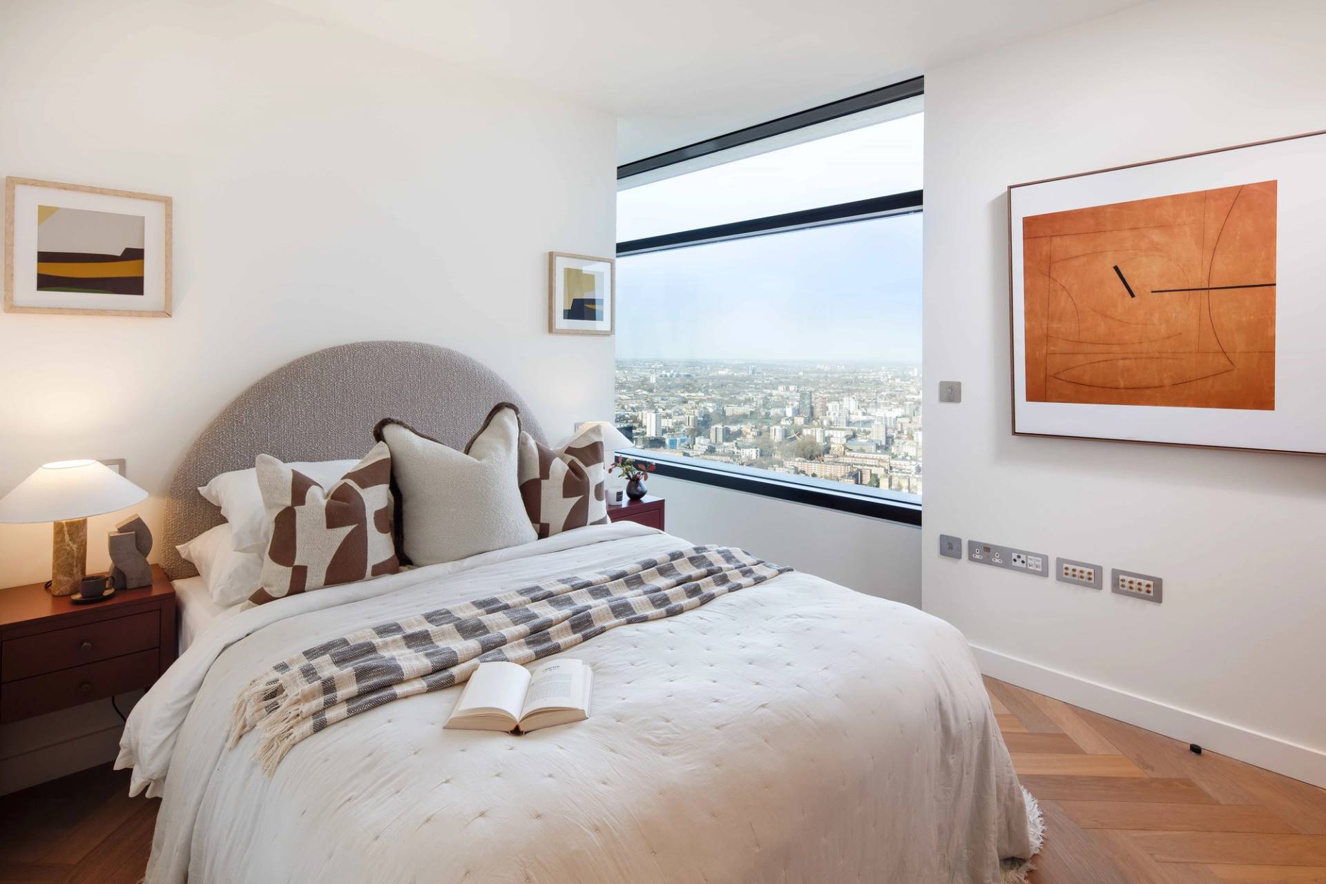 Bright secondary guest bedroom featuring a neutral upholstered headboard, terracotta wall art, and city view sash window, perfect for home decor lookbooks, Love Locations.
