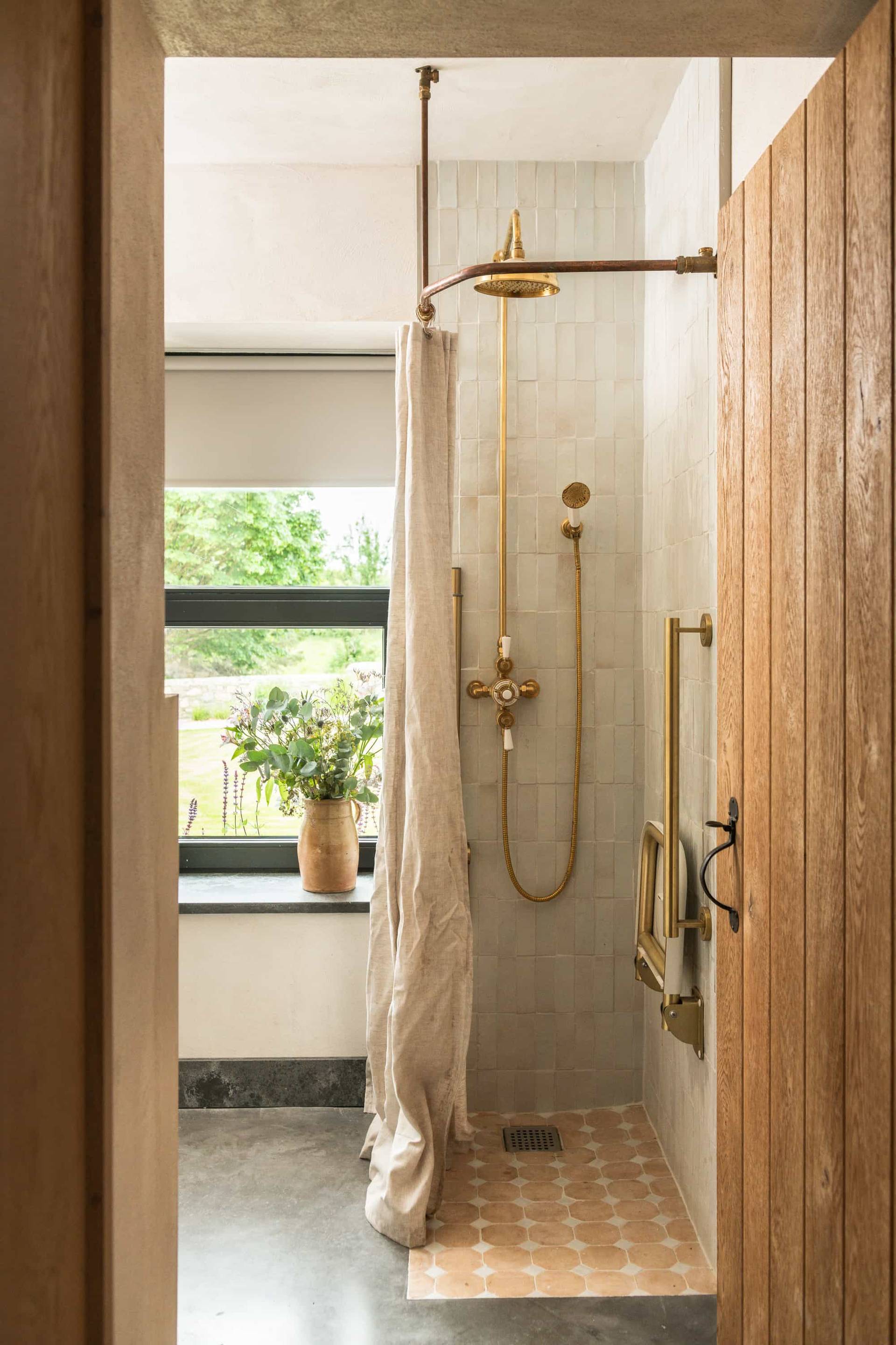 En-suite shower room location house in Castleblayney County Monaghan Ireland by Love Locations, with a walk-in shower, brass rainfall showerhead, and natural green views.