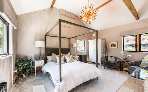 Luxury master bedroom location space featuring a modern black metal four-poster bed and vaulted ceilings, Love Locations Essex.