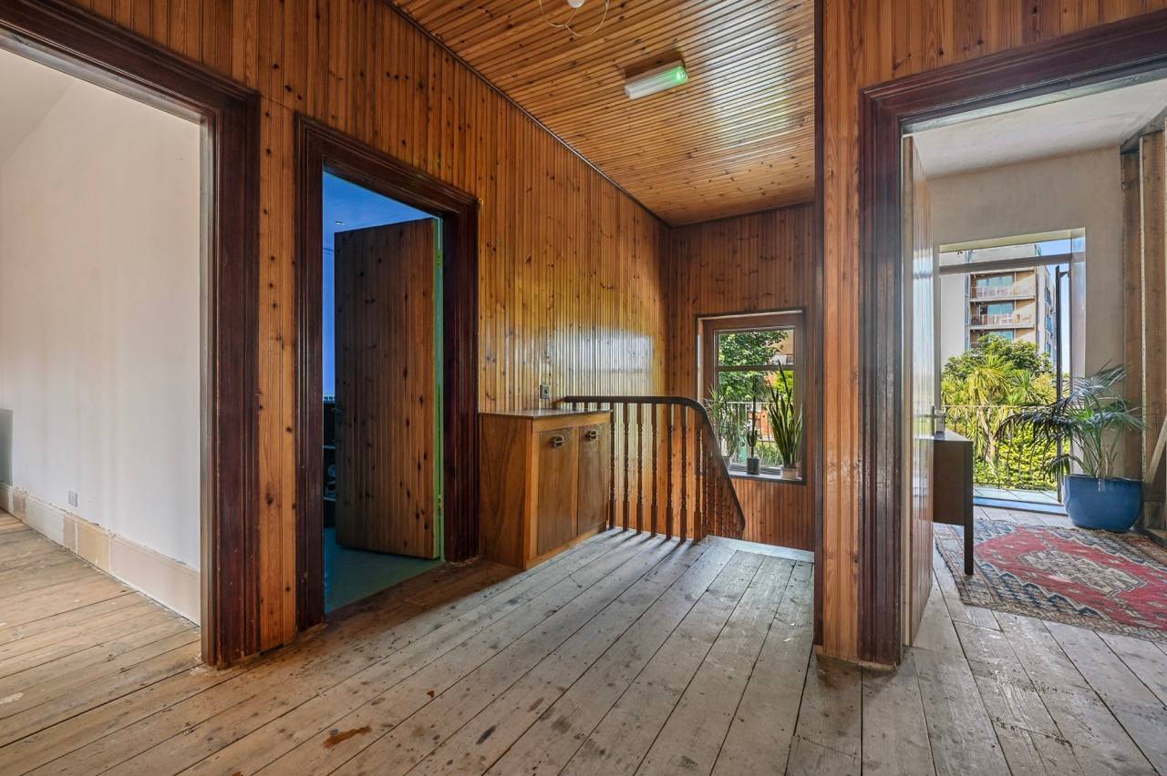 Upper stairwell landing featuring full pine wood panelling, rustic floorboards, and timber doors, Love Locations.