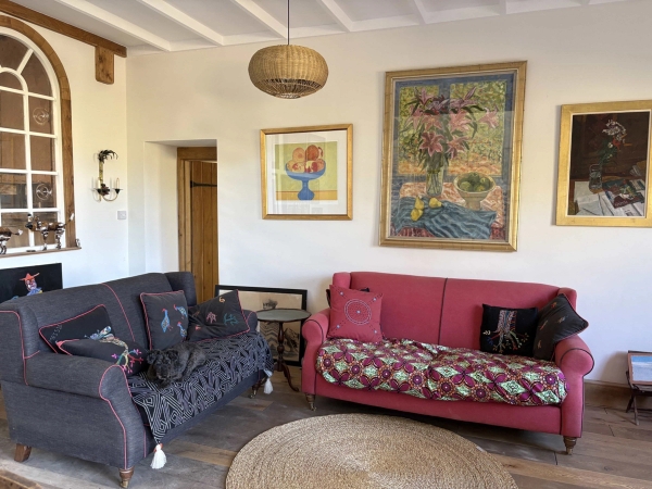 Rustic farm cottage living room with eclectic sofas, colorful wall art, and exposed timber ceiling joists in Lewes, Love Locations BN8.