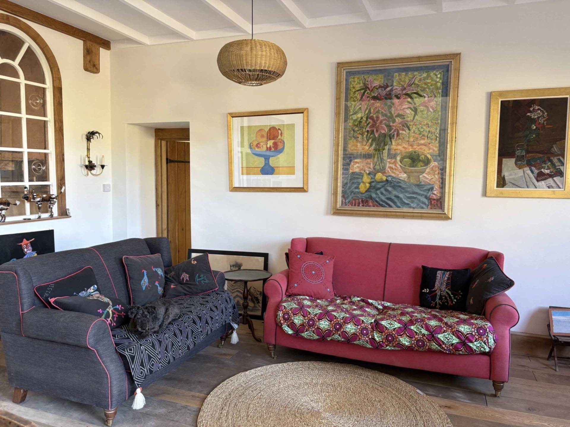 Rustic farm cottage living room with eclectic sofas, colorful wall art, and exposed timber ceiling joists in Lewes, Love Locations BN8.