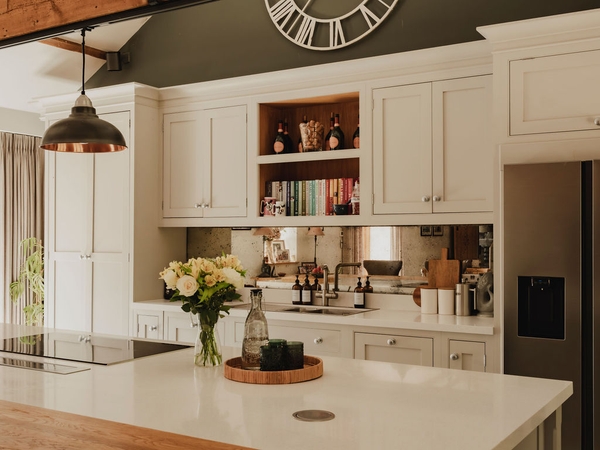 Sleek kitchen island counter with fresh flowers and mirror splashback detail inside a luxury rural barn conversion, Love Locations.