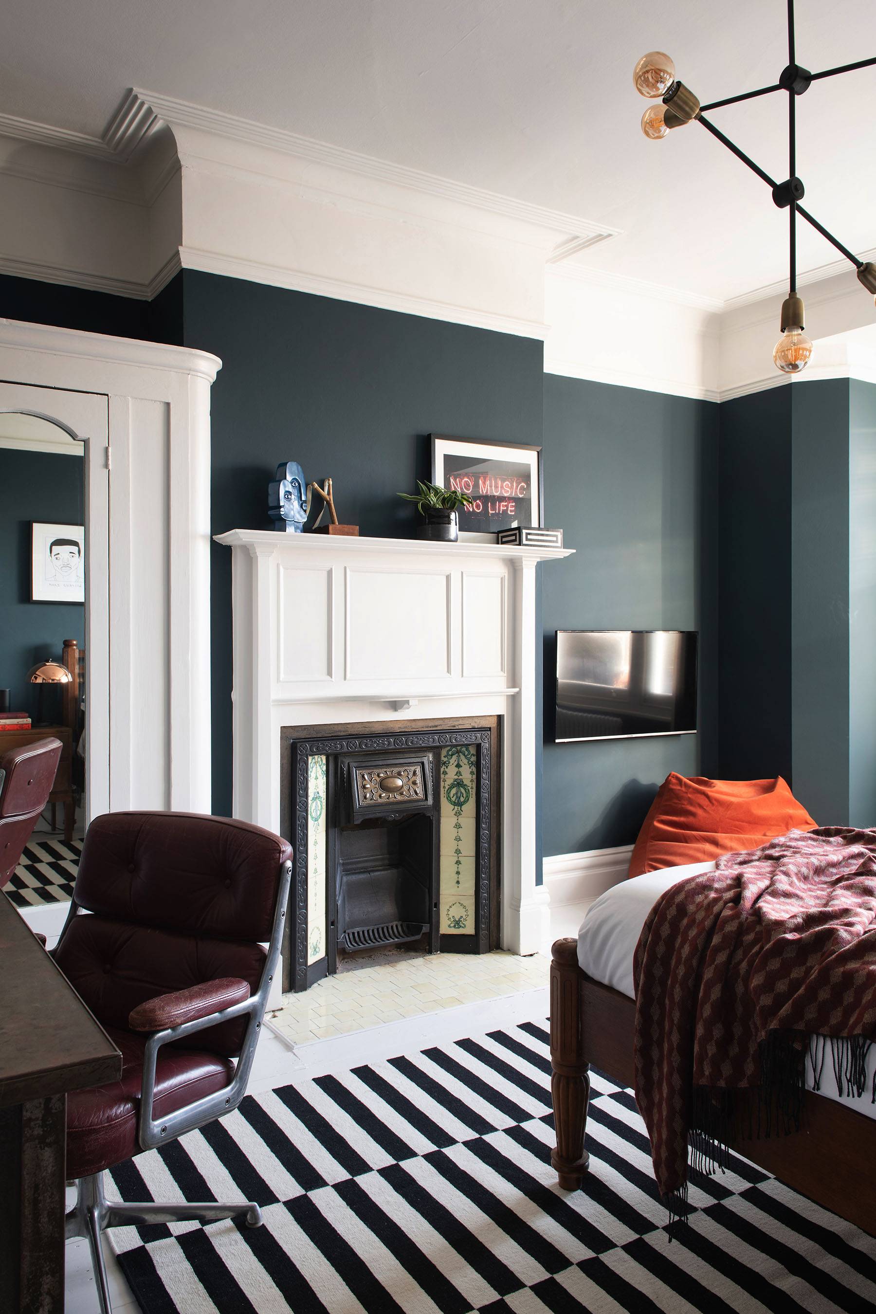 Home office study nook in a dark teal bedroom with vintage wooden desk, leather chair, and window light, Love Locations.