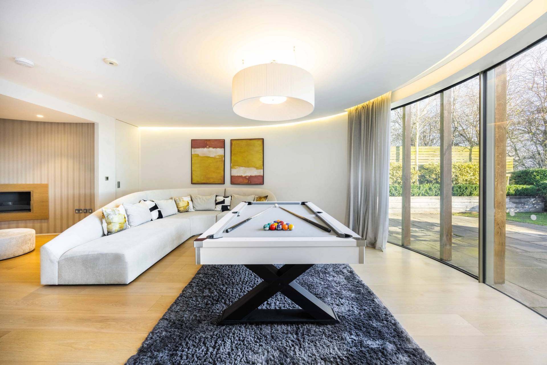 Games room featuring a contemporary white pool table set on a plush charcoal area rug, Love Locations WD7.