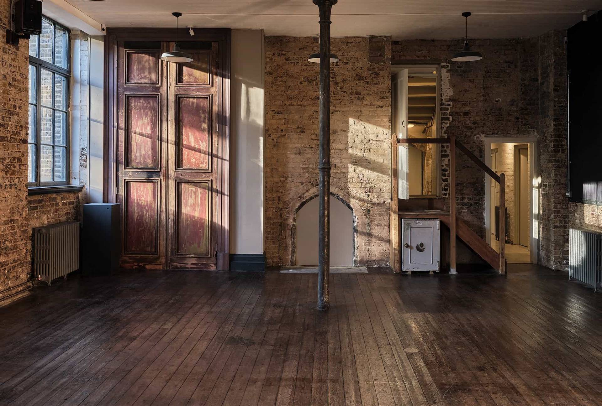 Industrial room detail showing double wooden doors and exposed brick walls set beside a timber pillar, Love Locations.